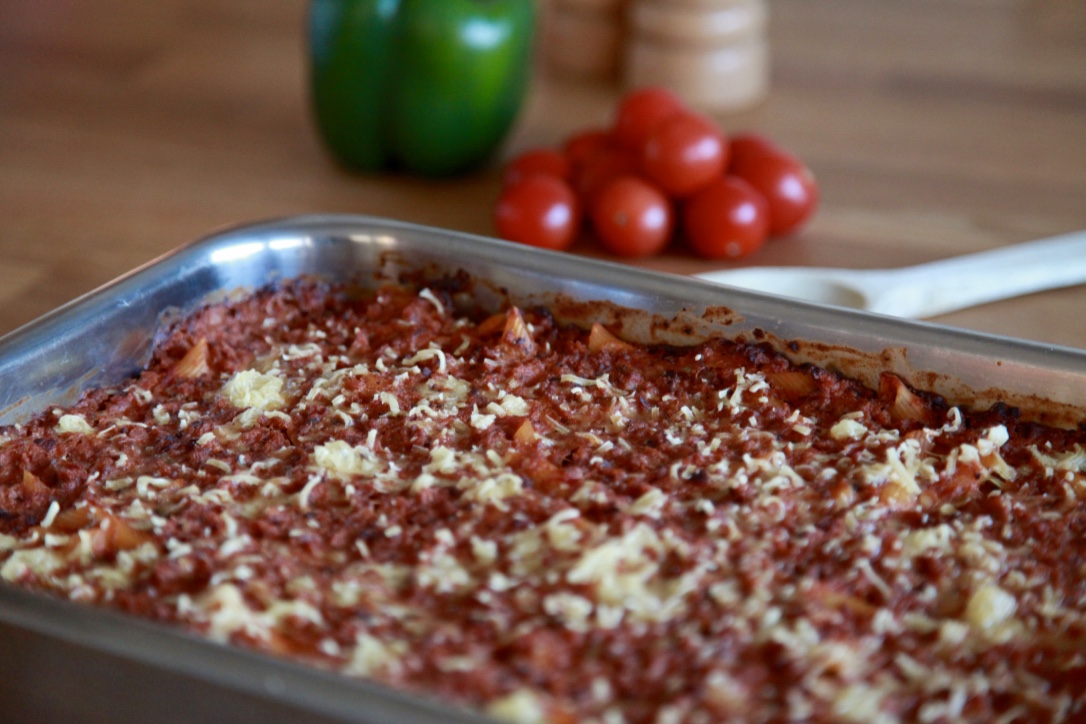 Lasagne i metallform, tomater i bakgrunden