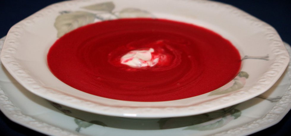 Röd soppa med en klick creme fraiche i mitten, serverad i vit, djup tallrik