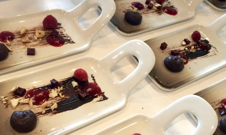 Avlånga serveringstallrikar med chokladcreme, hallon och halloncrispflaarn på