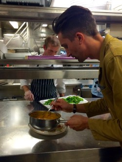 Maximilian häller sås över maträtt i köket på Birka