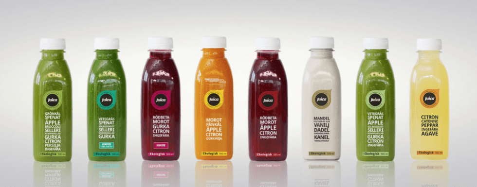 Åtta stycken flaskor med vit kork, etiketter som anger olika smaker på framsidan.