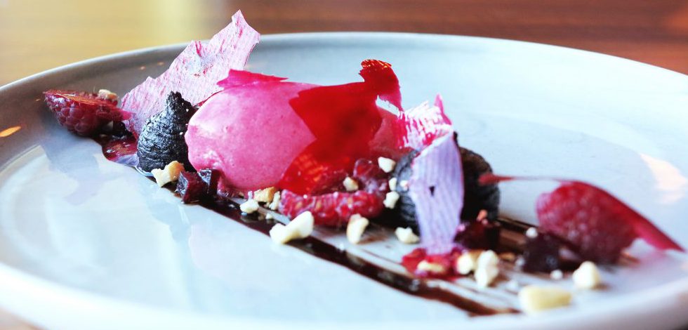 Hallonsorbet med hackade nötter och choklad på vit tallrik