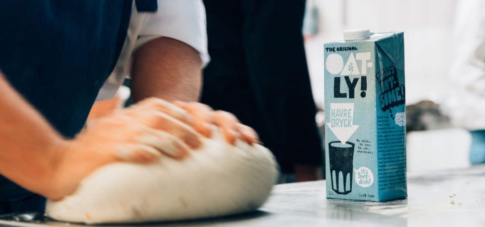 En deg knådas på bakbord, bredvid står en tetraförpackning med Oatly havredryck