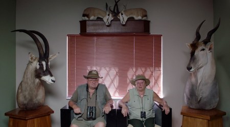 En man och en kvinna sitter i varsin fåtölj omgivna av uppstoppade djur. 