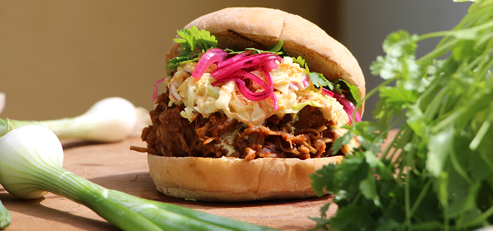 Burgare med bröd och grönsaker, till vänster en lök och höger salladsblad.