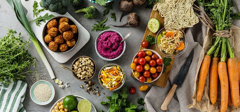 Grönsaker i skålar och på skärbrädor sedda uppifrån, majsbollar i en skål till vänster