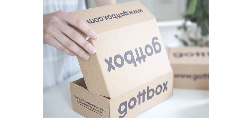 En kartong med texten gottbox på, som öppnas, hand syns till vänster