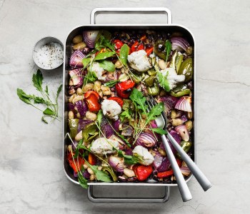 Rektangulär aluminiumform sedd uppifrån med ugnsbakade bönor och grönsaker