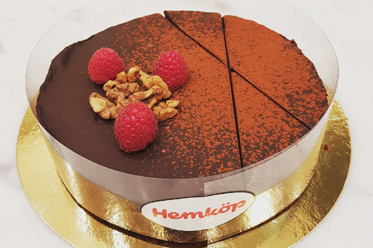 Chokladtårta sedd uppifrån på en guldplatta, garnerad med tre färska hallon