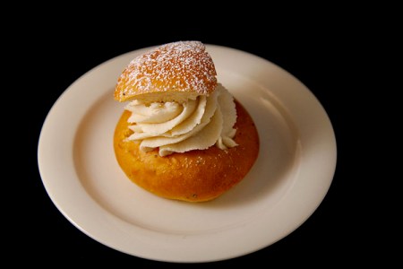 Semla på vitt fat mot svart bakgrund