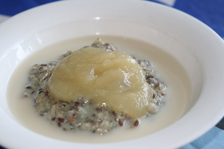 Vit tallrik med gröt toppad med äppelmos, mjölk runt om