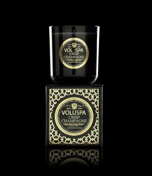 Svart värmeljus i glas ovanpå en guld- och svartfärgad förpackning