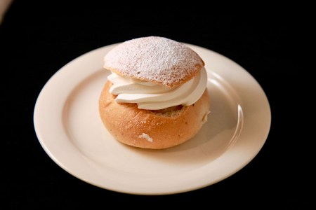 Semla på vitt fat mot svart bakgrund