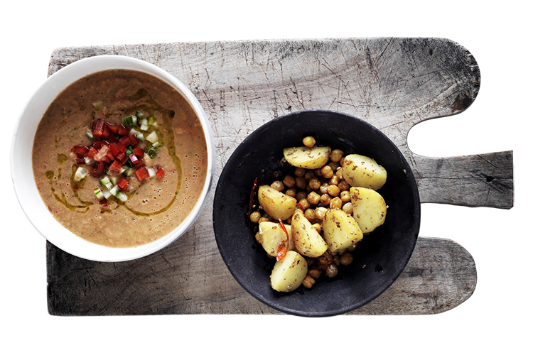 Två skålar på en skärbräda. Soppa i den vänstra, potatis i den högra