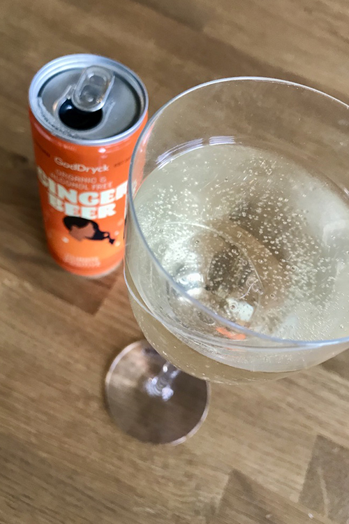 Ett glas med ljus bubblig dryck, bredvid en orange burk med texten Ginger Beer