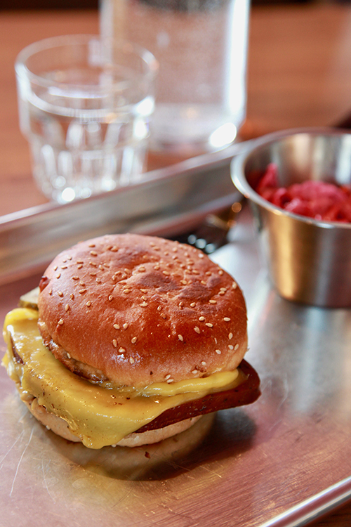 Cheeseburgare på bricka, till höger en skål med slaw
