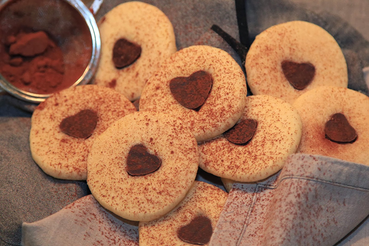 Ljusa, runda kakor med chokladhjärta i mitten, kakao pudrat över