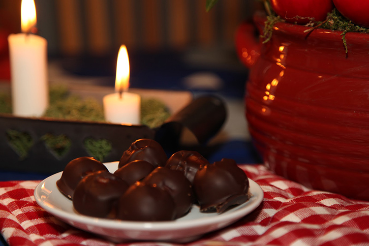 Chokladbollar på ett fat, i bakgrunden en adventsljusstake med tända ljus