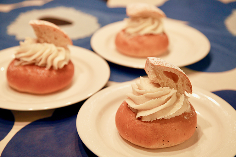 Semla på fat, tre stycken på ett bord med blåblodig duk