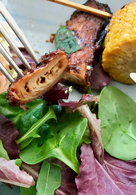 En bit majskolv, bredvid en "rib". En gaffel har spetsat en bit avskuren rib