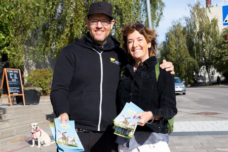 En an håller armen om en kvinna, båda håller informationsfoldrar "Varför vegan?" i händerna.