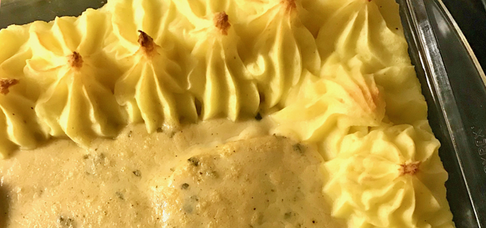 Spritsat potatismos runt kanten på en ugnsform, sås bredvid