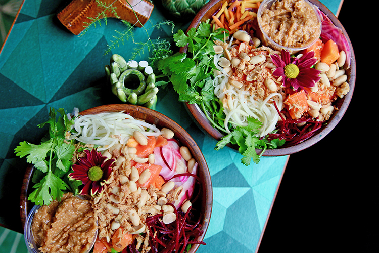 Två skålar i teak med sallad, en blomma och en röra