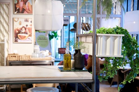 Ljusa bord med vita lampor över. Vid sidan gröna växter