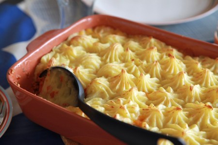 Rektangulär keramikform med spritsat mos med en svart slev i hörnan