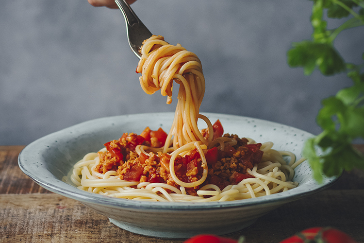 En tallrik med spaghetti bolognese. En gaffel med upprullad spaghetti
