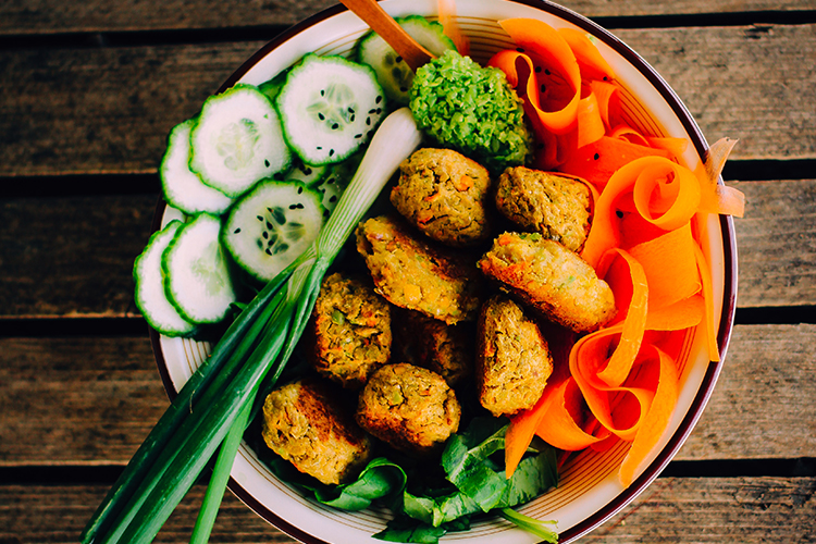 Skål med färsk gurka, salladslök strimlad morot och falafel i mitten
