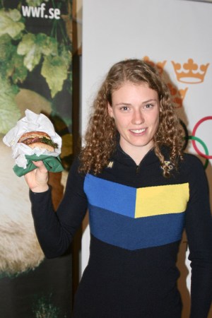 En leende kvinna håller upp en hamburgare