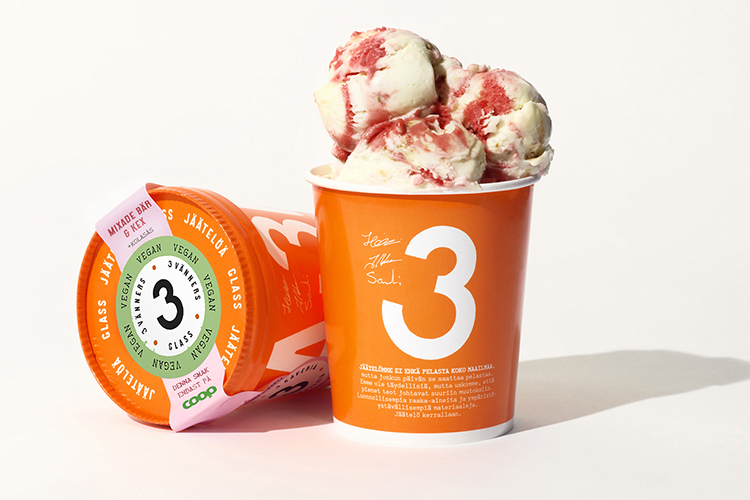 Två orangea glassbägare, en liggande med lock, den anta med glass som sticker upp, en vit 3:a på förpackningen