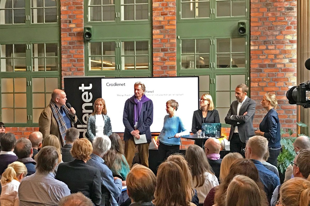 Sju personer står framför en publik