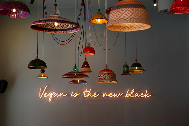 Lampor hänger från taket och på väggen står det "Vegan is the new black"