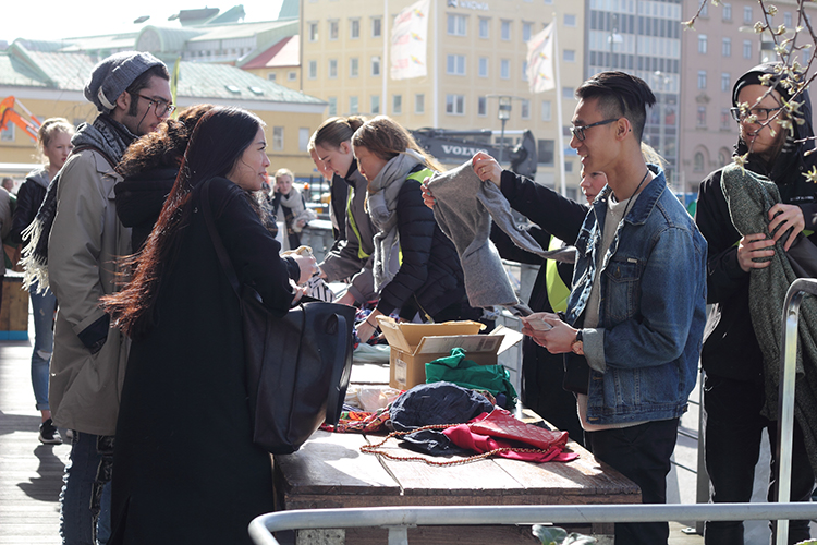 Folk står runt bord på loppis